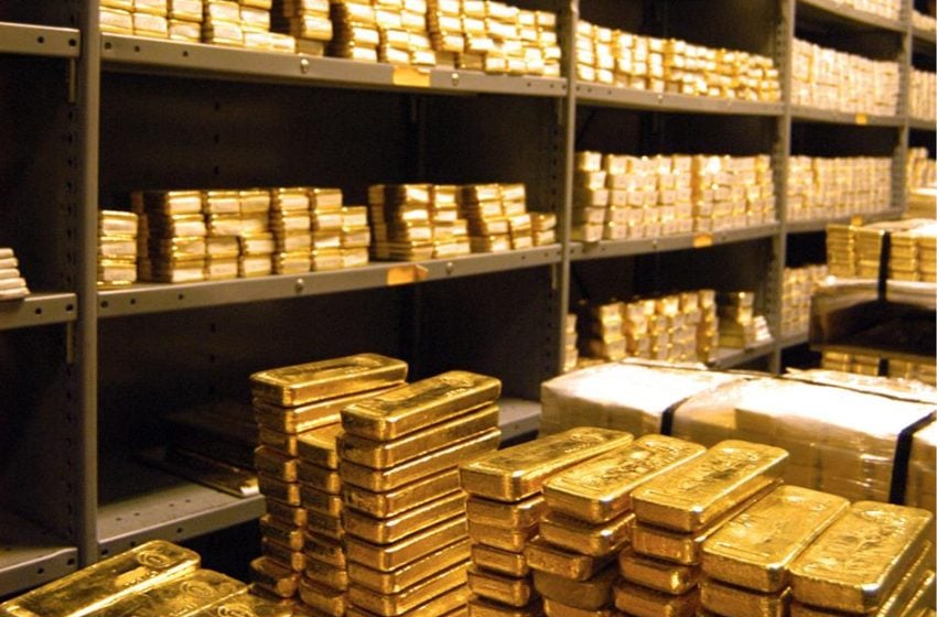 Stacks of gold bars stored in a secure vault with metal shelves – symbol of wealth, investment, and financial security