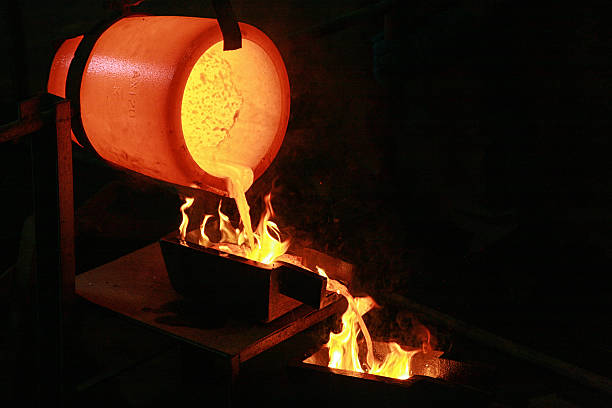 Molten gold being poured from a crucible into molds at a gold refinery, illustrating the gold smelting process in industrial mining.